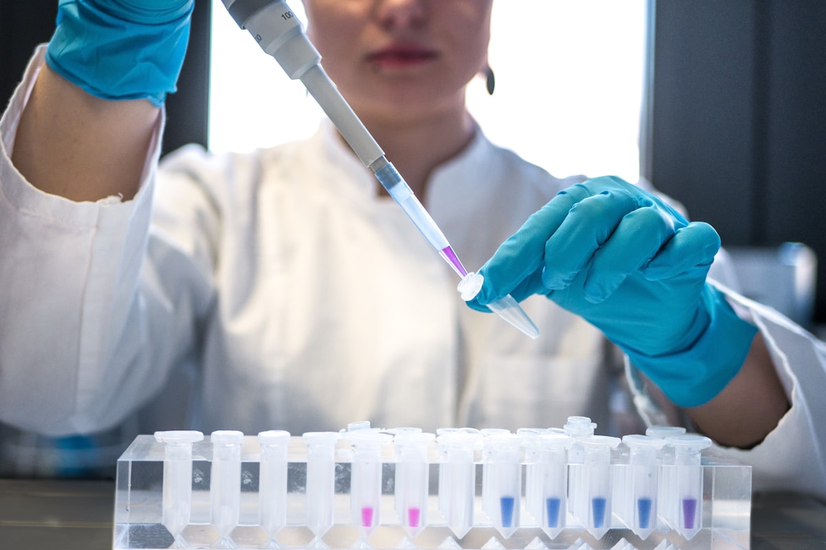 Researcher pipetting coloured samples into vials in a laboratory